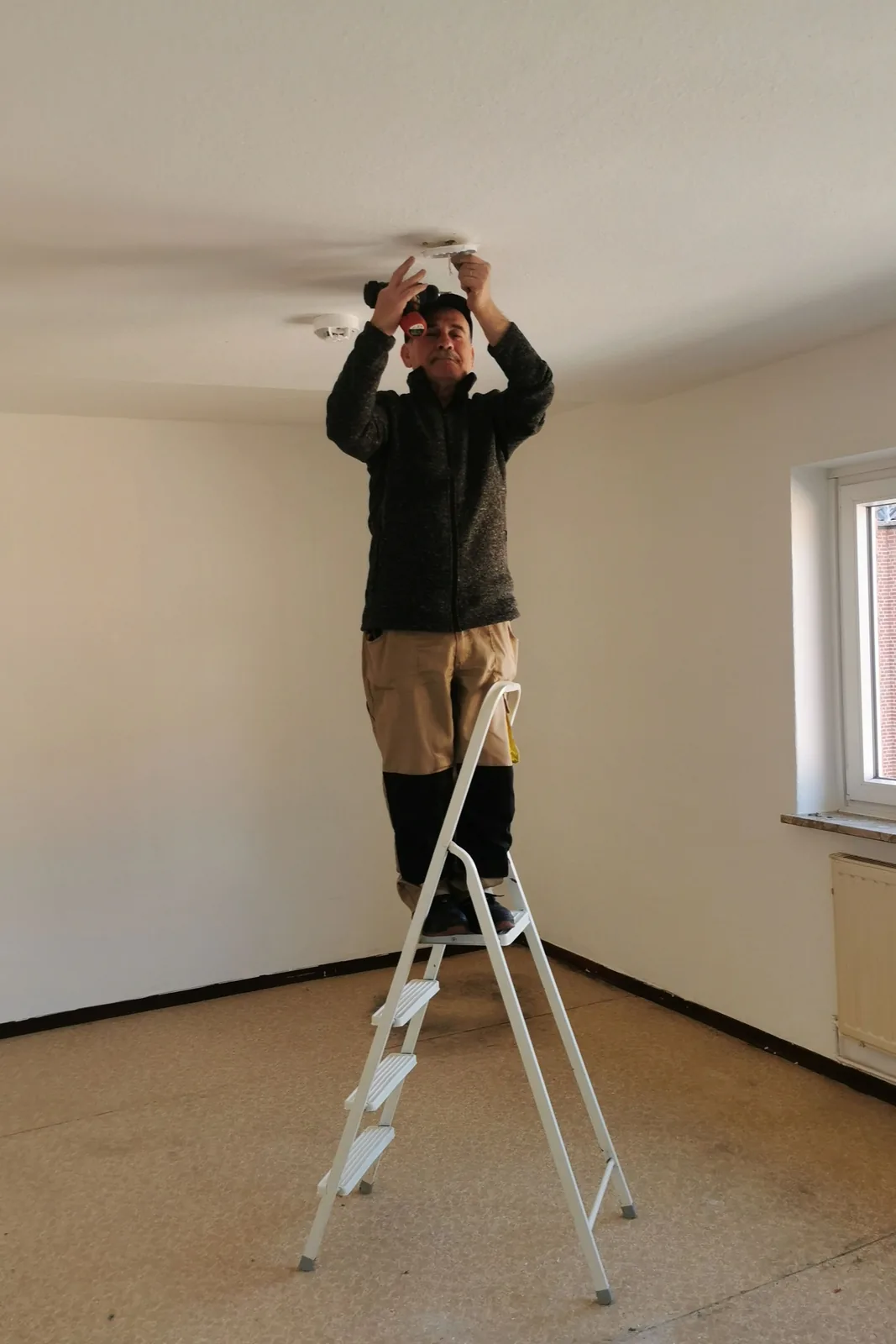 Fitting a ceiling detector from a step ladder, for ceiling fan installation in Edmonton