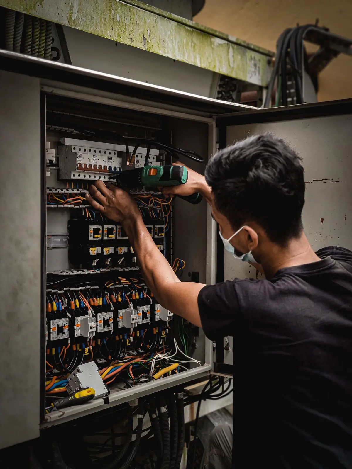 An electrician working inside a large distribution board, for pot light installation in Edmonton