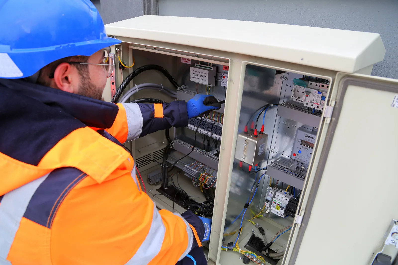 An electrician working in an outdoor service cabinet, for maintenance plans in Edmonton
